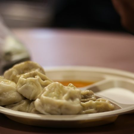 a plate of dumplings with dipping sauce on a table